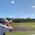 A skeet shooter firing at a clay target. Gulf Coast Clays